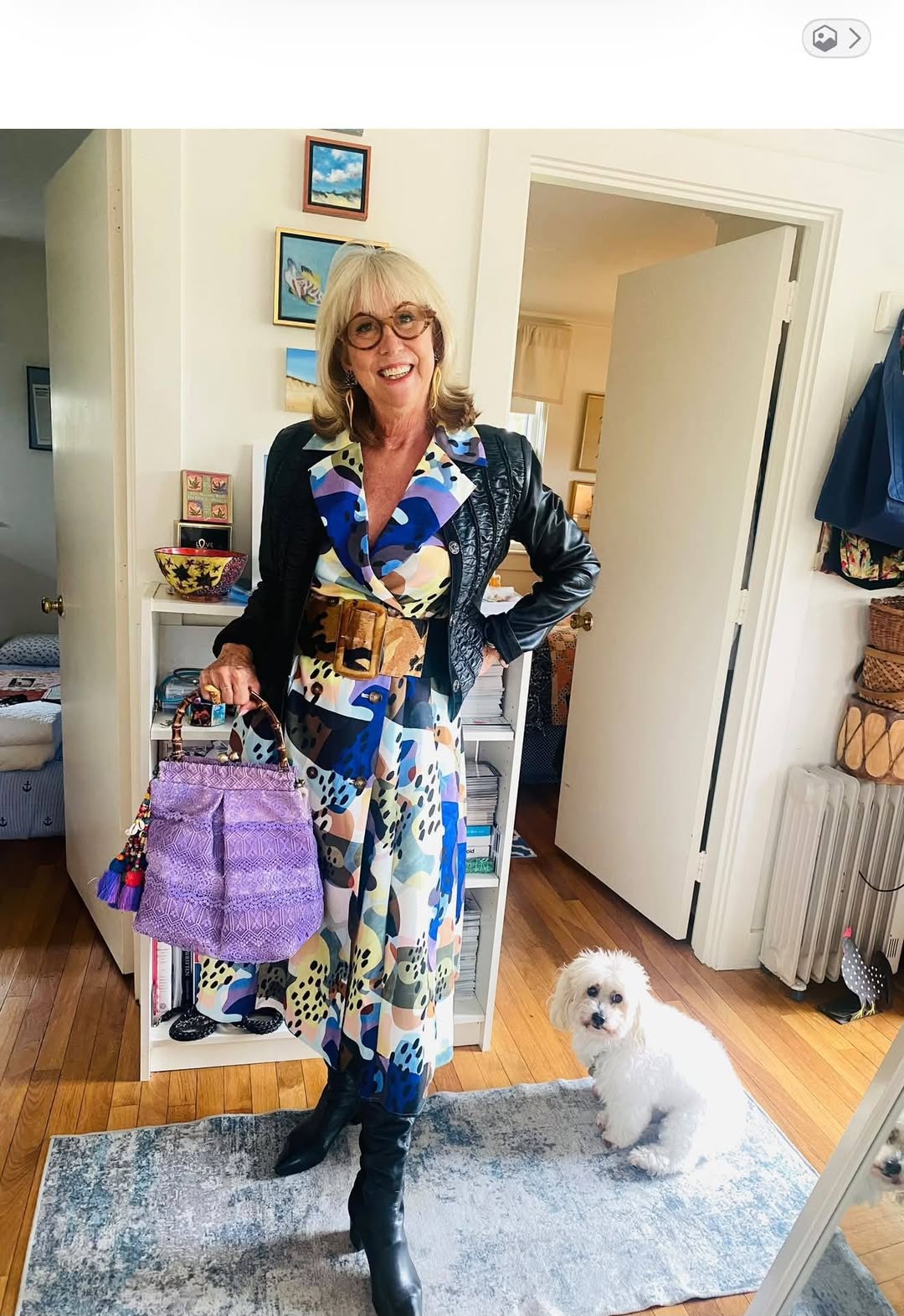 Bonnie Roseman at home with her dog, in a printed dress and leather jacket